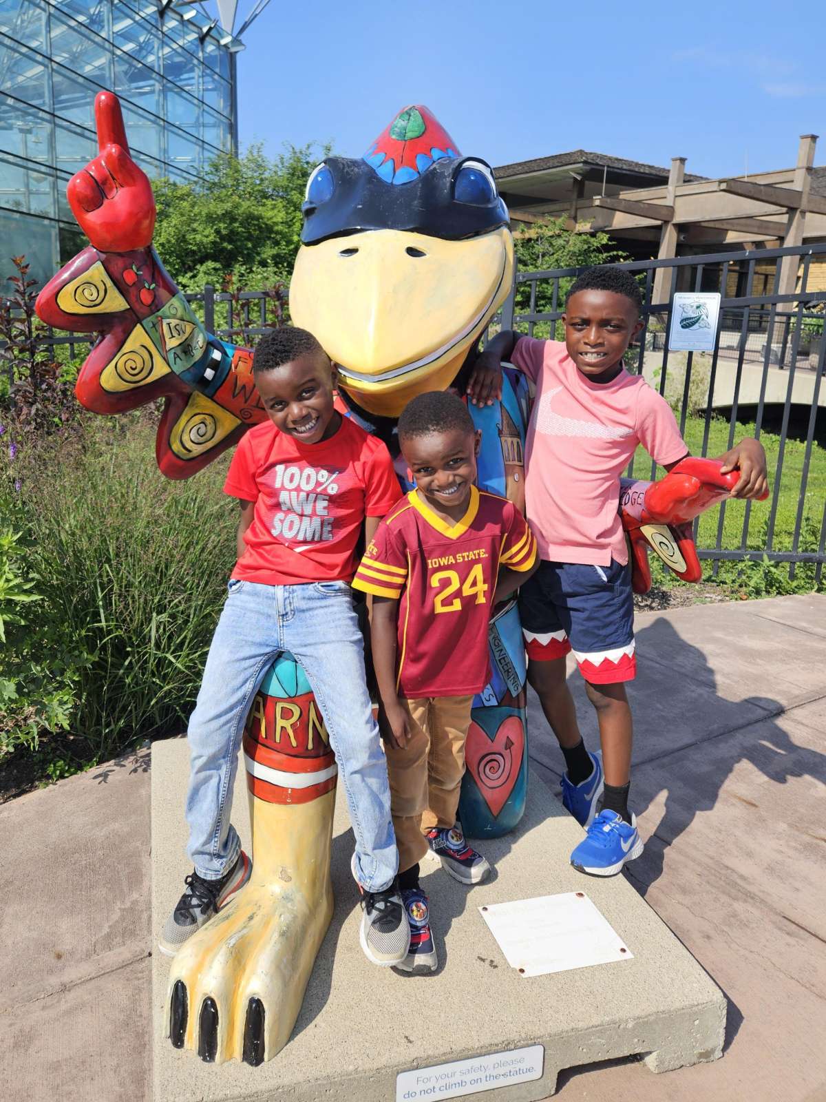Children posing with statue of Cy outside Reiman Gardens