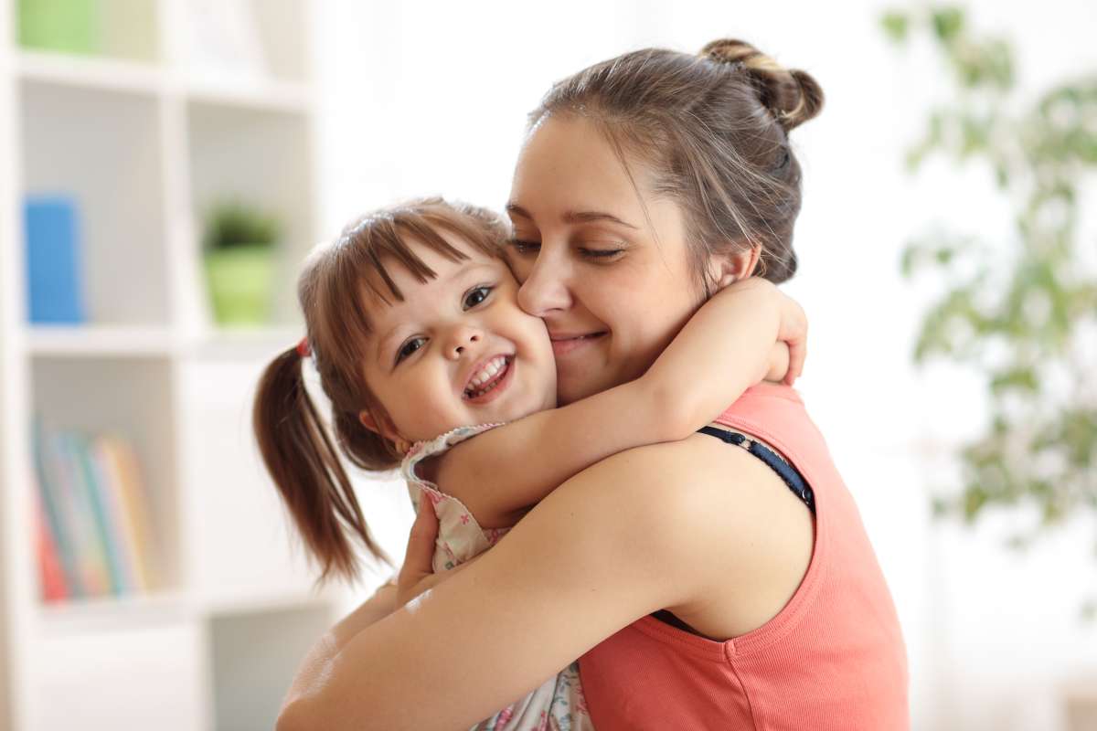 Young mom hugging toddler daughter