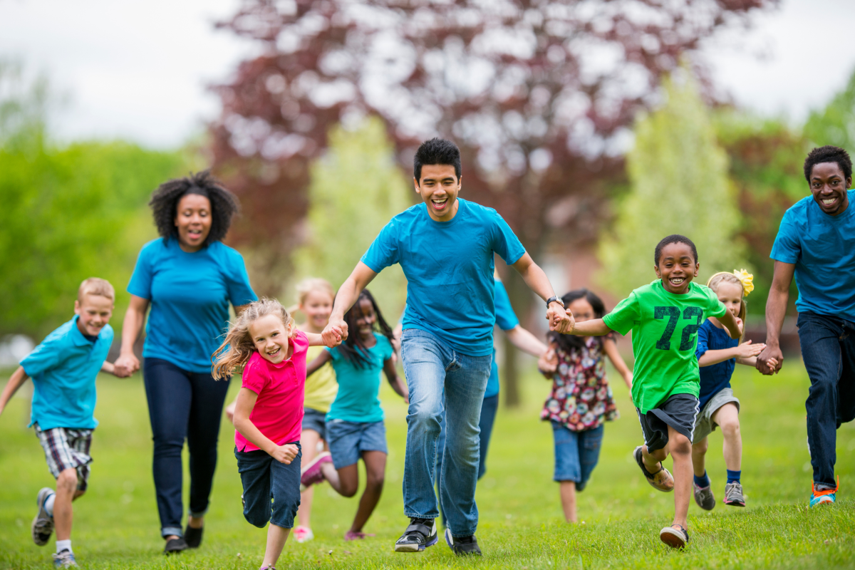 School age children playing game outdoors with teachers