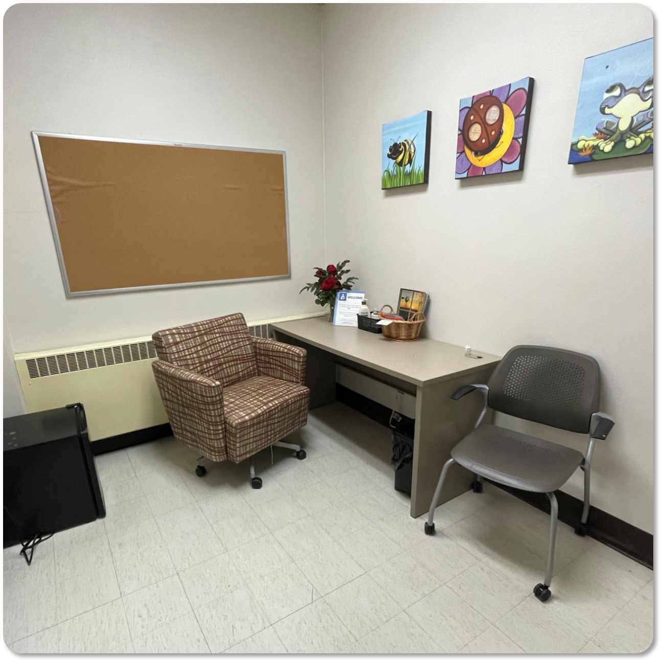 Cork board and desk and two chairs in room